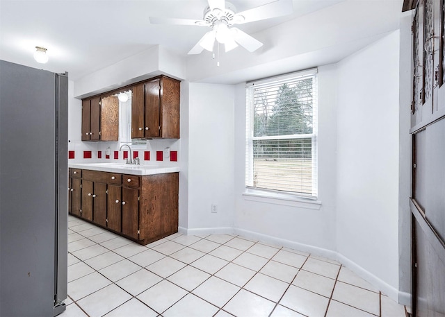 kitchen featuring ceiling fan, dark brown cabinetry, sink, and light tile patterned floors