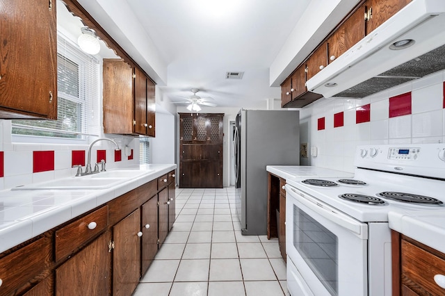 kitchen with white electric stove, tile countertops, ceiling fan, and decorative backsplash