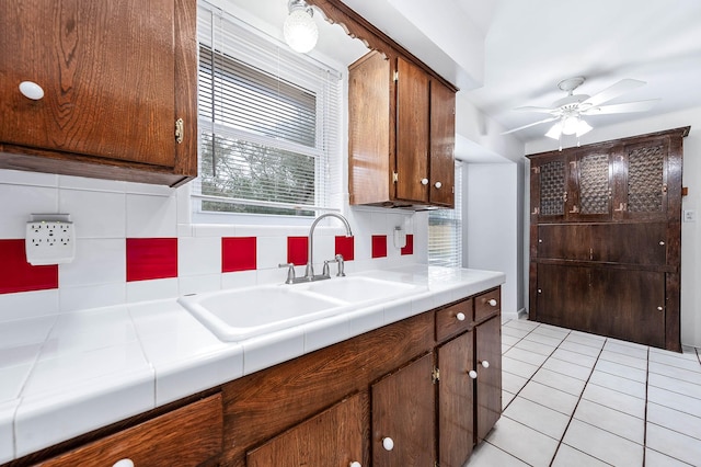 kitchen featuring tile countertops, tasteful backsplash, sink, light tile patterned floors, and ceiling fan