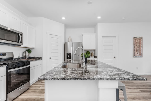 kitchen with appliances with stainless steel finishes, sink, and a center island with sink