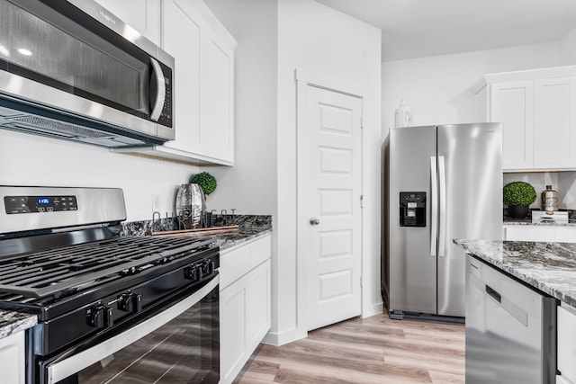 kitchen with light stone counters, white cabinetry, light hardwood / wood-style flooring, and stainless steel appliances