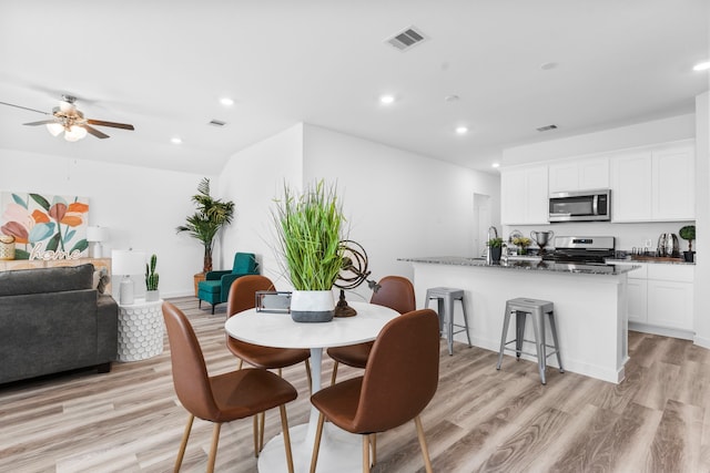 dining area featuring ceiling fan, sink, and light wood-type flooring