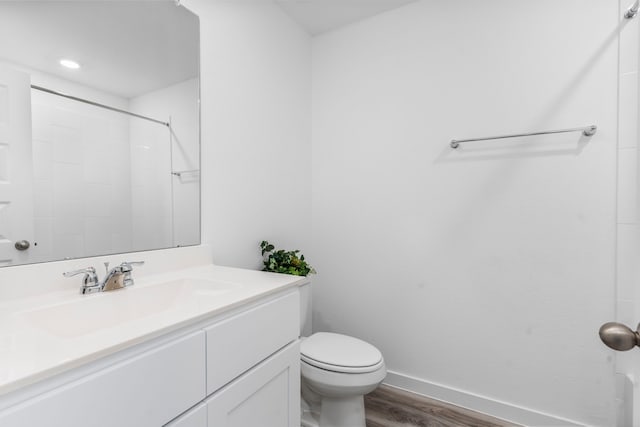 bathroom featuring vanity, hardwood / wood-style flooring, a shower, and toilet