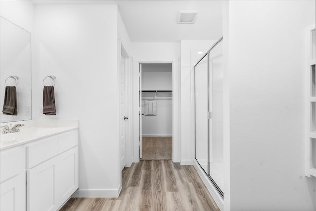 bathroom featuring an enclosed shower, vanity, and wood-type flooring