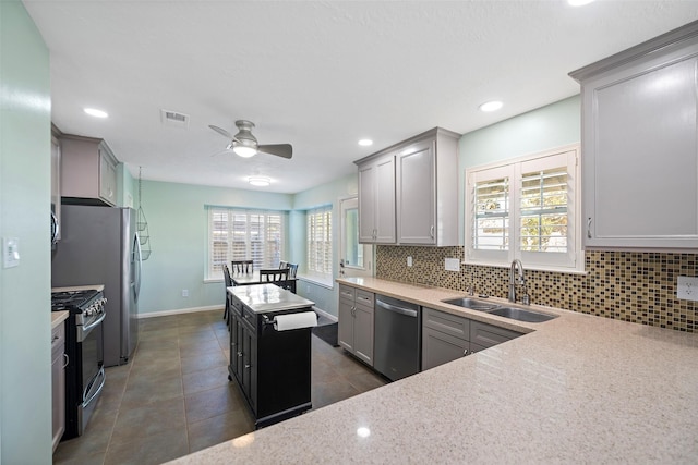 kitchen featuring a kitchen island, appliances with stainless steel finishes, sink, gray cabinetry, and backsplash