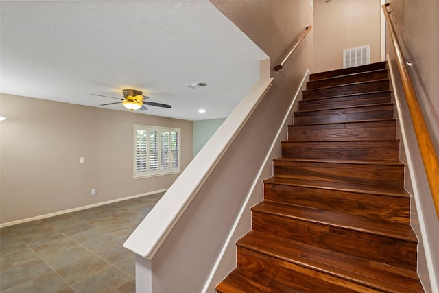 stairway featuring ceiling fan