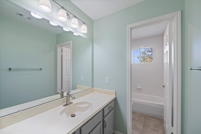 bathroom featuring tiled shower / bath, vanity, and tile patterned flooring