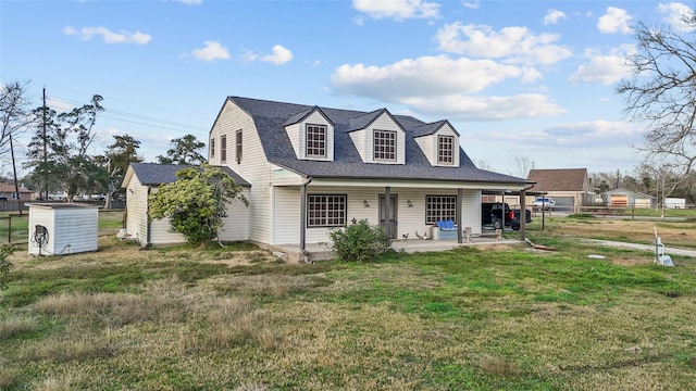 view of front of property with an outbuilding, a shingled roof, fence, a shed, and a front lawn