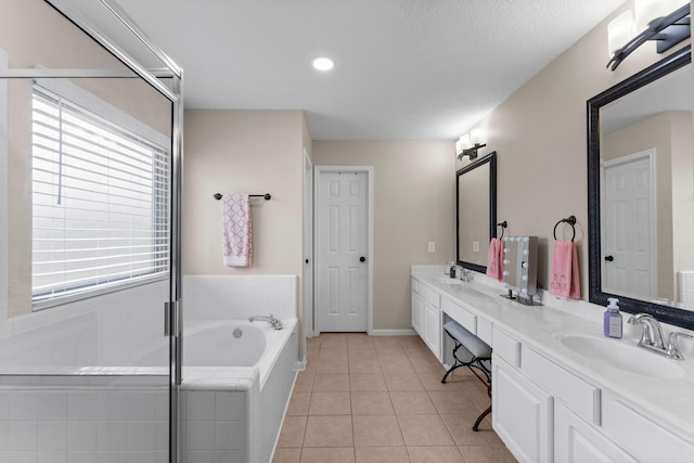 bathroom featuring a relaxing tiled tub, tile patterned floors, and vanity