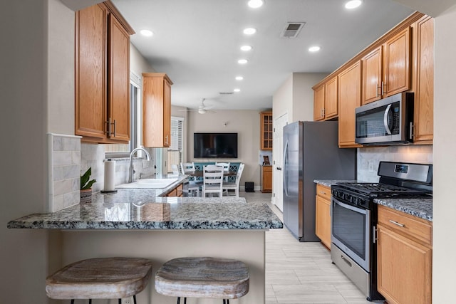 kitchen with sink, a breakfast bar area, stainless steel appliances, and kitchen peninsula