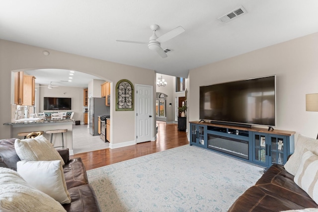 living room with light hardwood / wood-style floors and ceiling fan with notable chandelier