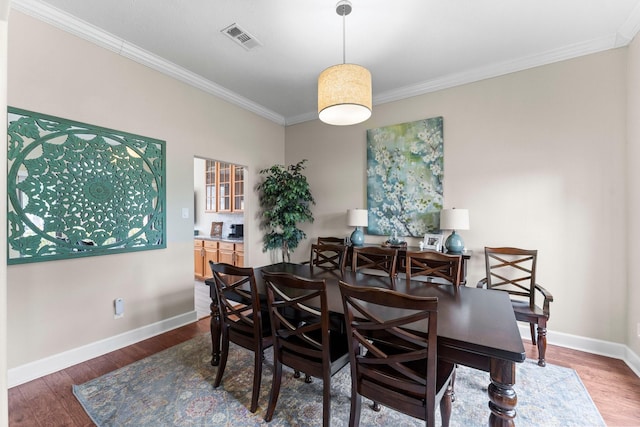 dining space with ornamental molding and dark wood-type flooring