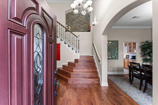 foyer entrance with crown molding, a notable chandelier, and dark hardwood / wood-style flooring