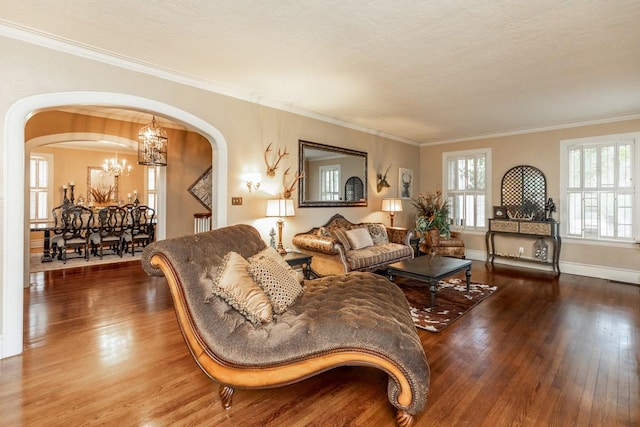 living room featuring crown molding, wood-type flooring, a textured ceiling, and a notable chandelier