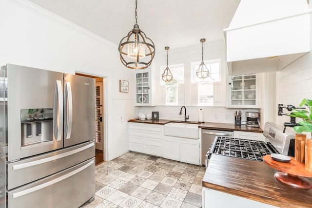 kitchen with pendant lighting, stainless steel appliances, sink, and white cabinets