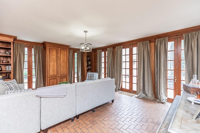 living room featuring a chandelier, french doors, and a healthy amount of sunlight