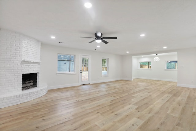 unfurnished living room featuring a fireplace, ceiling fan, and light wood-type flooring