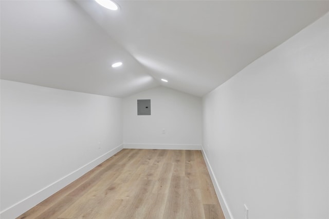 additional living space featuring electric panel, vaulted ceiling, and light hardwood / wood-style flooring