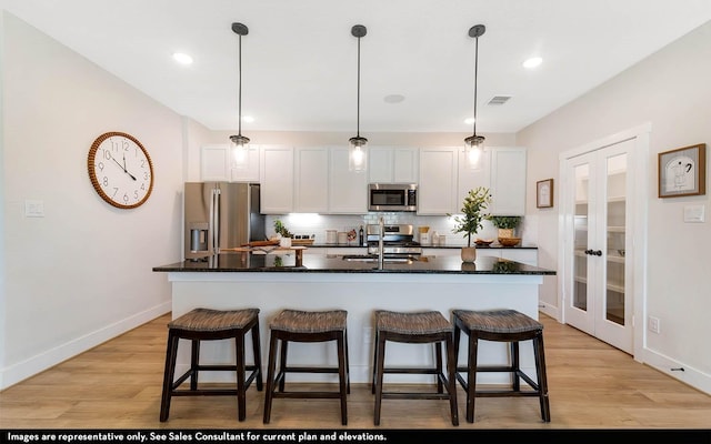 14123 Gingko Ct, Crosby, TX 77532 - kitchen with appliances with stainless steel finishes, a kitchen island with sink, french doors, a kitchen bar, and tasteful backsplash