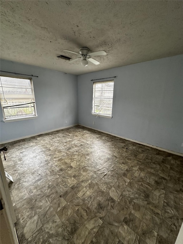 empty room with a textured ceiling and ceiling fan