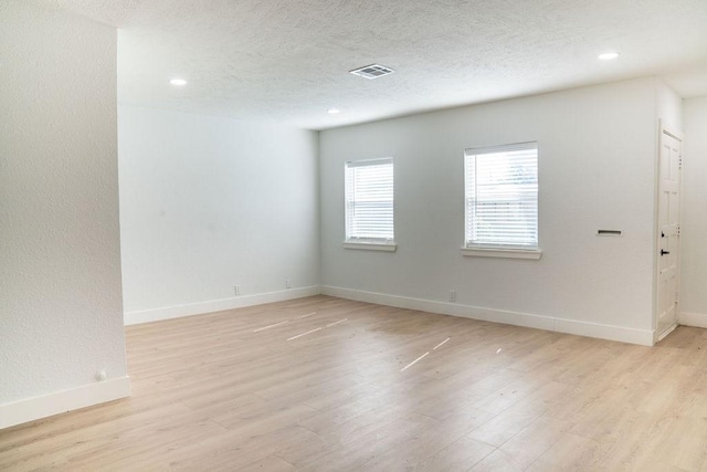 spare room with light hardwood / wood-style flooring and a textured ceiling