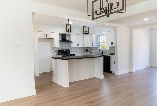 kitchen featuring wall chimney exhaust hood, white cabinetry, hanging light fixtures, black dishwasher, and stove