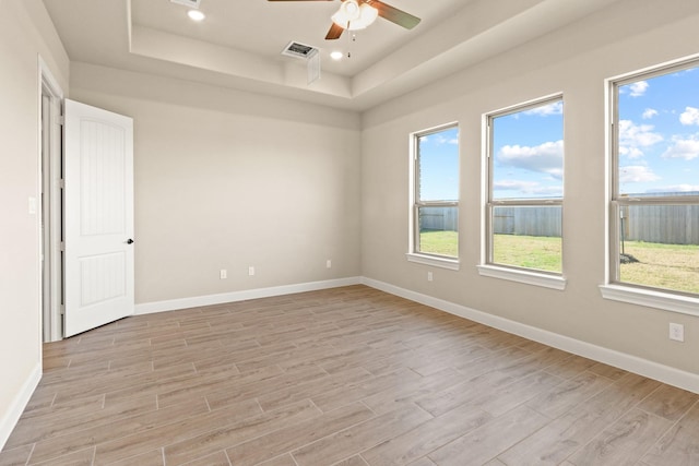 unfurnished room with ceiling fan, a raised ceiling, and light wood-type flooring