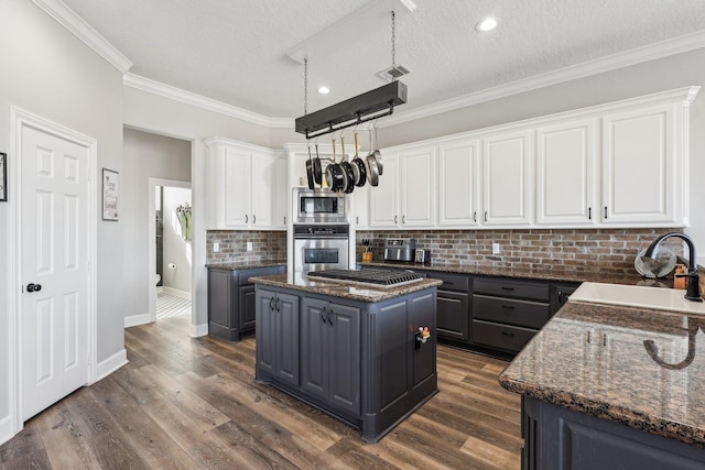 kitchen with gray cabinetry, stainless steel appliances, white cabinets, a kitchen island, and dark stone counters