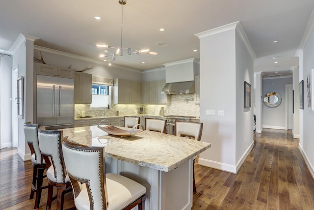 kitchen featuring light stone counters, a center island, decorative light fixtures, high end appliances, and backsplash