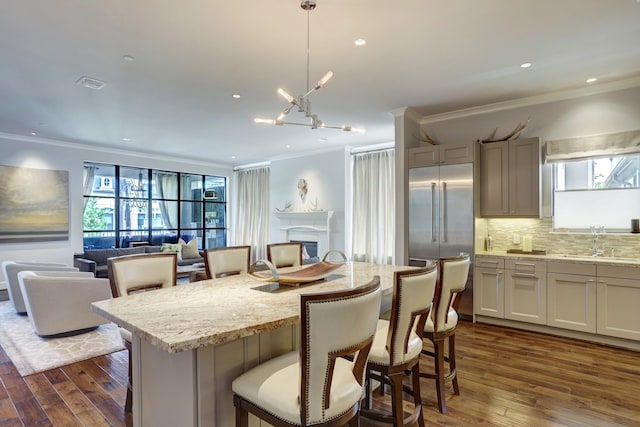 kitchen featuring a breakfast bar, visible vents, open floor plan, stainless steel built in fridge, and pendant lighting