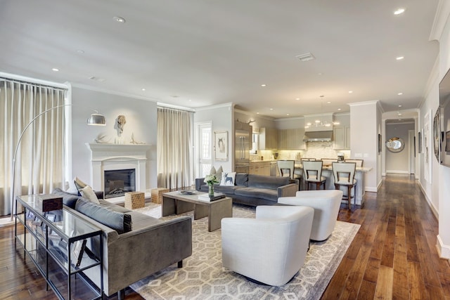 living room featuring baseboards, a glass covered fireplace, ornamental molding, wood finished floors, and recessed lighting