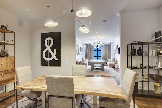 dining area with dark wood-type flooring, visible vents, ornamental molding, and an inviting chandelier