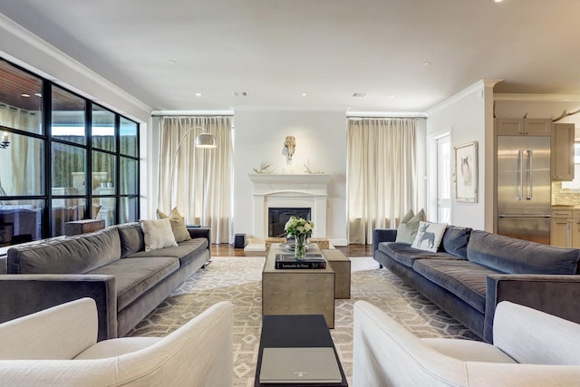 living area with recessed lighting, light wood-type flooring, a glass covered fireplace, and crown molding