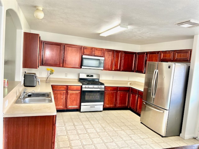 kitchen featuring stainless steel appliances, sink, and a textured ceiling