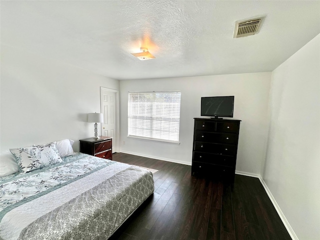 bedroom with dark hardwood / wood-style flooring and a textured ceiling