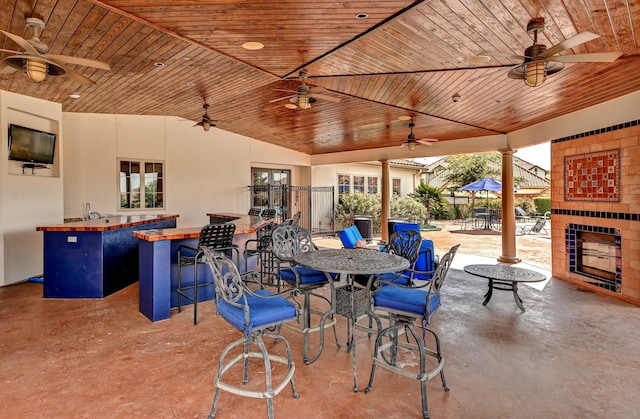 view of patio with ceiling fan, exterior bar, and exterior fireplace