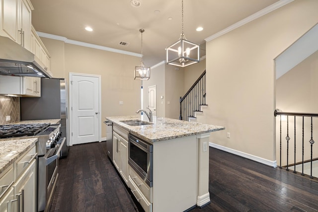 kitchen featuring pendant lighting, sink, light stone counters, stainless steel appliances, and a center island with sink