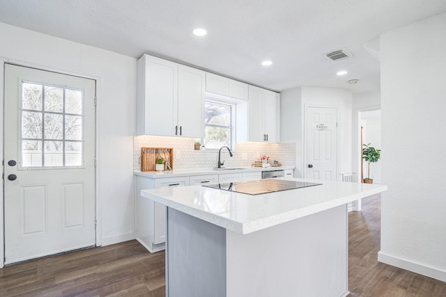 kitchen with backsplash, a sink, white cabinets, and a center island