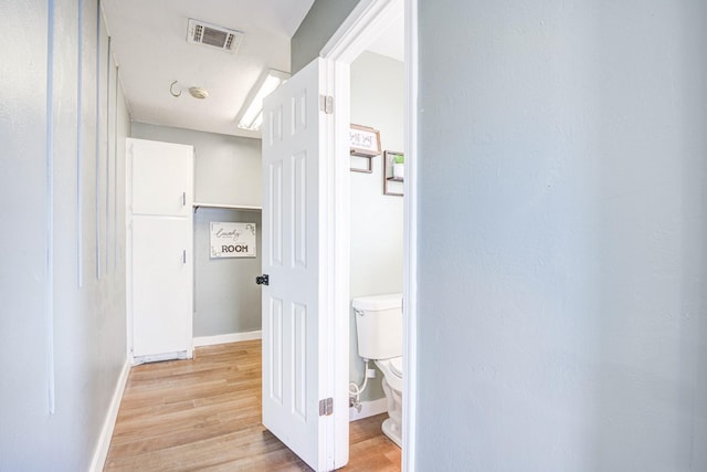 corridor featuring light wood-style flooring, visible vents, and baseboards