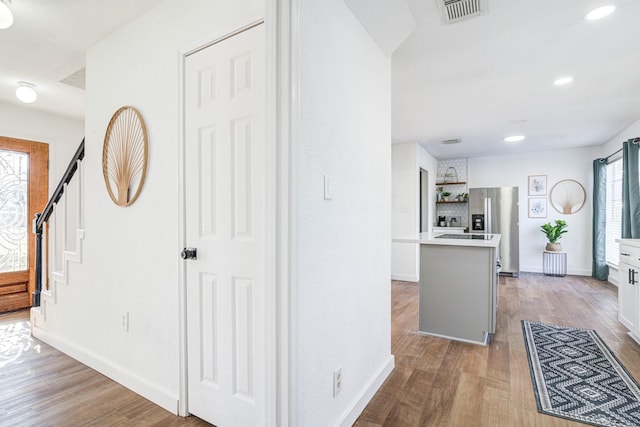 hallway with recessed lighting, visible vents, baseboards, stairs, and light wood finished floors