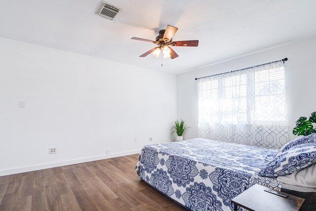 bedroom featuring baseboards, visible vents, ceiling fan, and wood finished floors