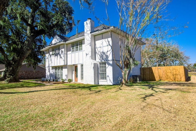 rear view of property with cooling unit and a lawn