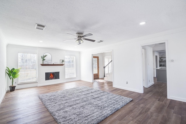 living room with plenty of natural light, ornamental molding, dark hardwood / wood-style floors, and a textured ceiling