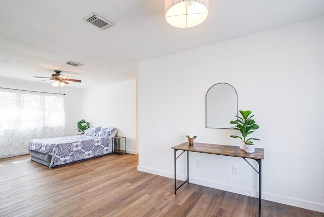 bedroom with wood finished floors, visible vents, and baseboards