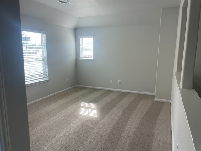 carpeted spare room with vaulted ceiling