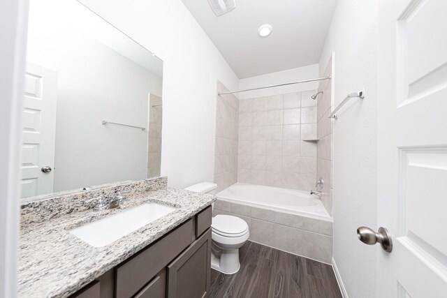 full bath with vanity, tiled shower / bath, toilet, and wood finished floors