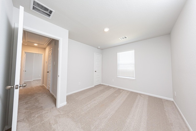 unfurnished bedroom featuring light carpet, visible vents, attic access, and baseboards