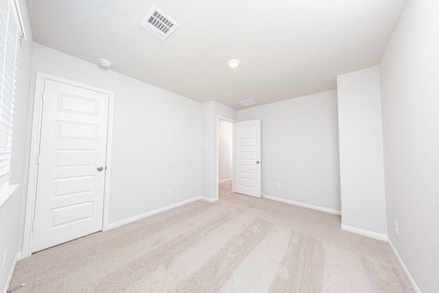 unfurnished room with baseboards, visible vents, and light carpet