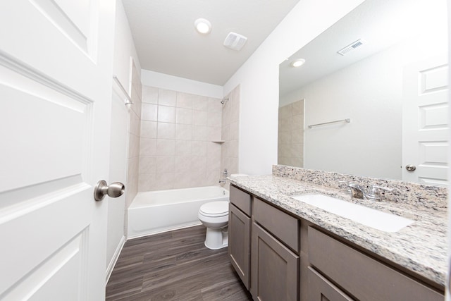 full bathroom featuring visible vents, toilet, vanity, wood finished floors, and washtub / shower combination