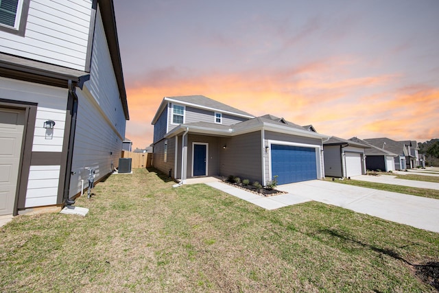 view of front of property featuring a lawn, central AC, fence, concrete driveway, and an attached garage